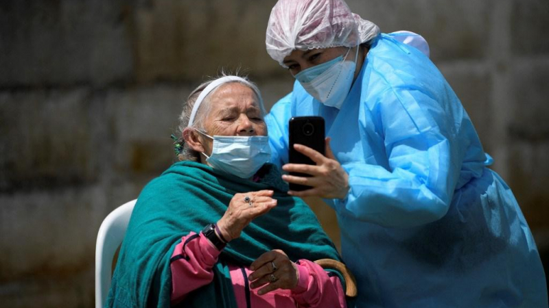 امرأة تحت رعاية أحد الممرضين بعد تلقي جرعة من لقاح كورونا في كولومبيا (أ ف ب).