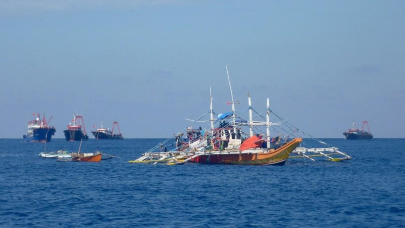 قوارب صيد فلبينية أمام مجموعة من السفن الصينية في بحر الصين الجنوبي (أرشيف).